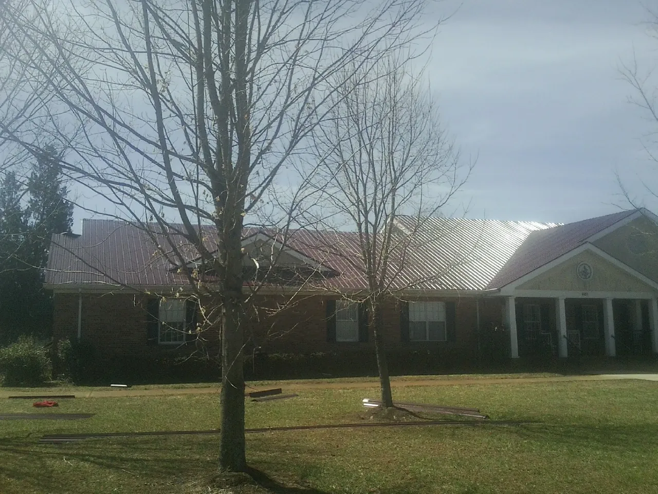 Red metal roof on a brick building seen from the front lawn in Jonesboro