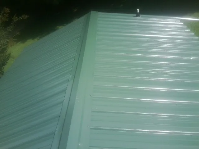 New green metal panels meeting at the ridge of a roof — Flat Roof Repair work by our crew in Jonesboro