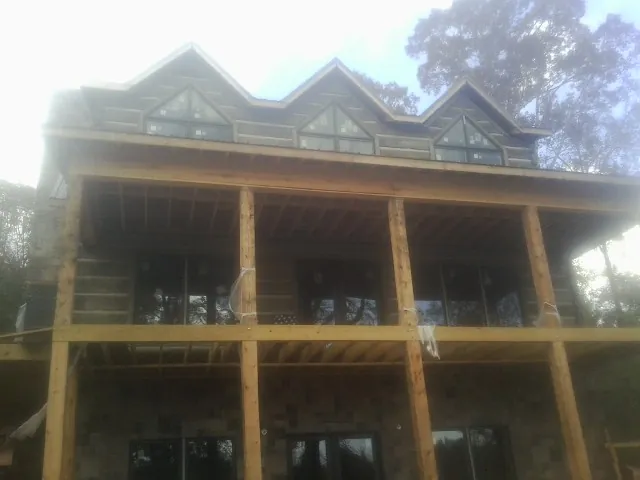 Dormers and porch framing on a large log home under construction — Roof Coating work by our crew in Jonesboro